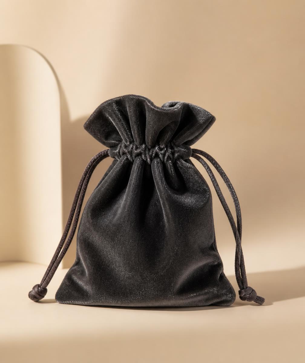 Deep charcoal organic velvet drawstring jewellery pouch on a warm beige backdrop